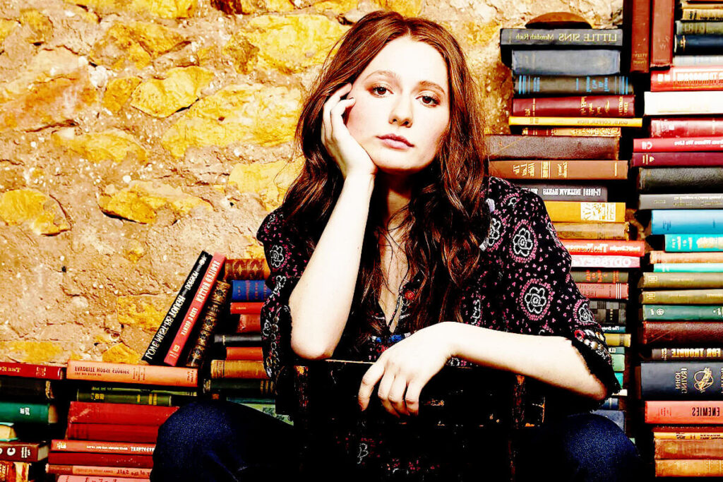 emma kenny sitting on chair with books backside